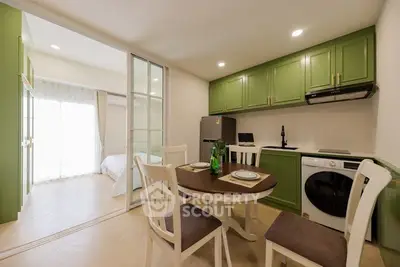 Charming open-layout kitchen with green cabinets and dining area, adjacent to a cozy bedroom.