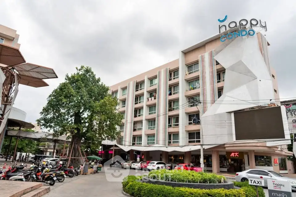 Modern condo building with parking area and lush greenery, ideal urban living space.