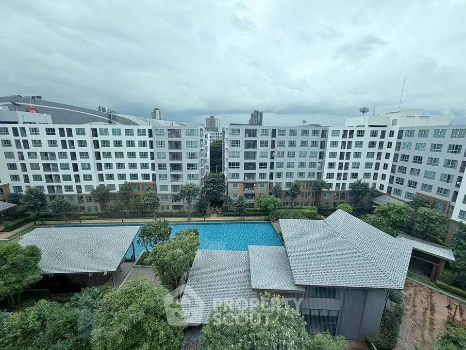 Stunning view of modern apartment complex with pool and lush greenery.
