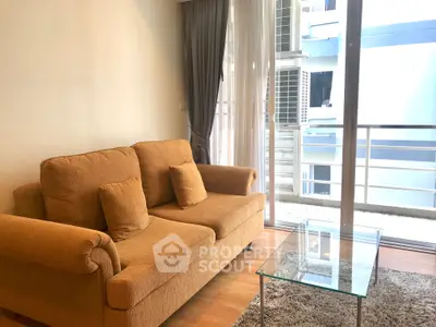 Cozy living room with plush sofa and glass coffee table, featuring floor-to-ceiling windows for natural light.