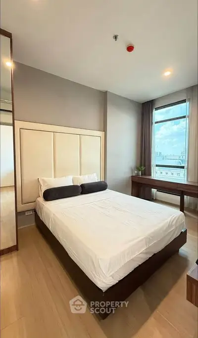 Modern bedroom with city view, featuring a stylish bed and elegant decor.