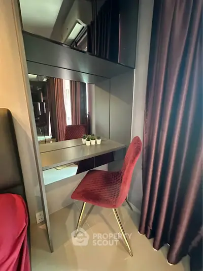 Elegant bedroom corner with plush red chair and mirrored vanity, perfect for modern living.