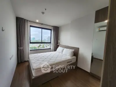 Modern bedroom with city view, featuring a cozy bed and stylish decor in a high-rise apartment.