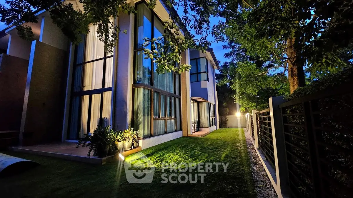Stunning modern home exterior with large windows and lush garden at twilight.