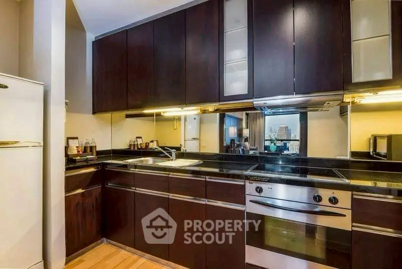 Modern kitchen with sleek dark cabinets and built-in oven, offering a stylish and functional cooking space.