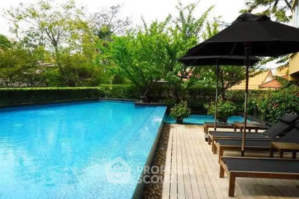 Luxurious outdoor pool area with sun loungers and lush greenery, perfect for relaxation.