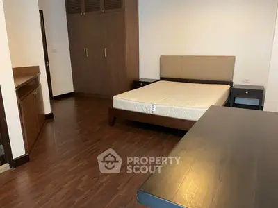 Spacious bedroom with wooden flooring and modern furniture in a stylish apartment.