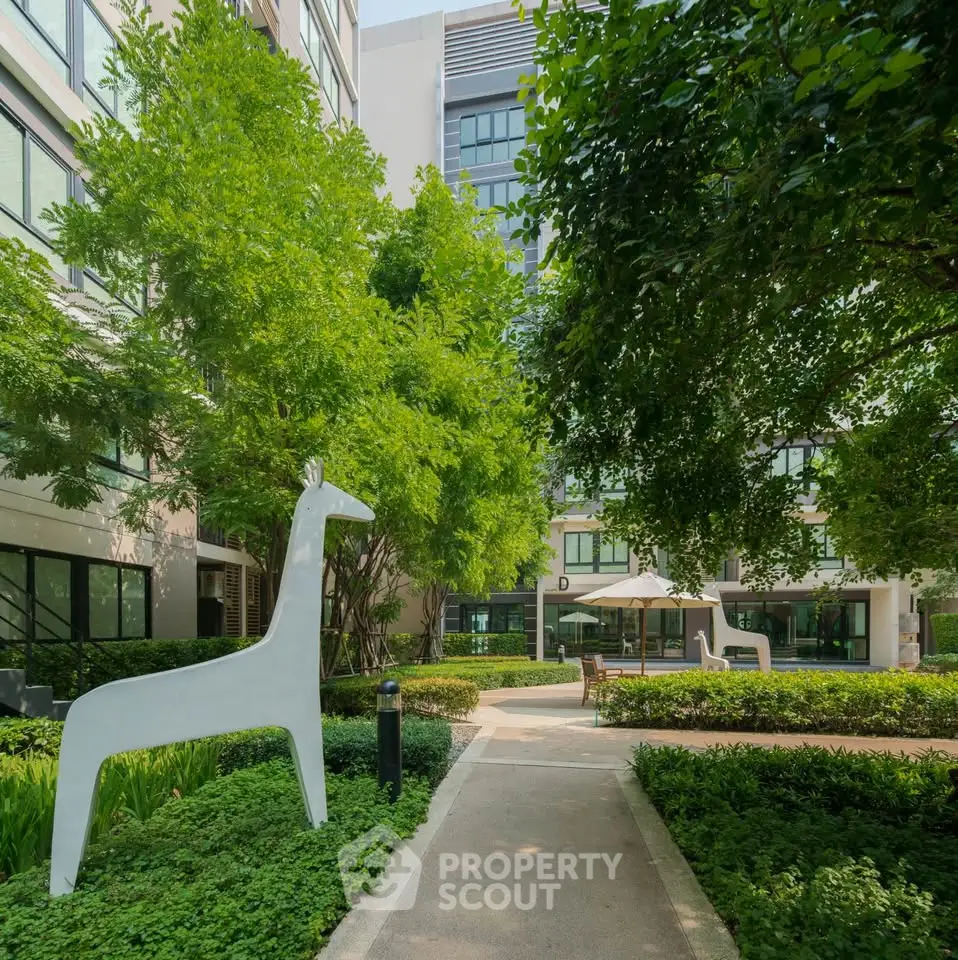 Modern apartment building with lush garden and unique giraffe sculptures