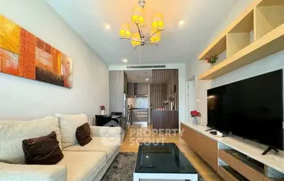 Modern living room with elegant decor and open kitchen layout, featuring a large TV and stylish lighting.