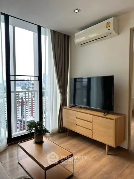 Modern living room with city view, featuring sleek TV setup and stylish wooden furniture.