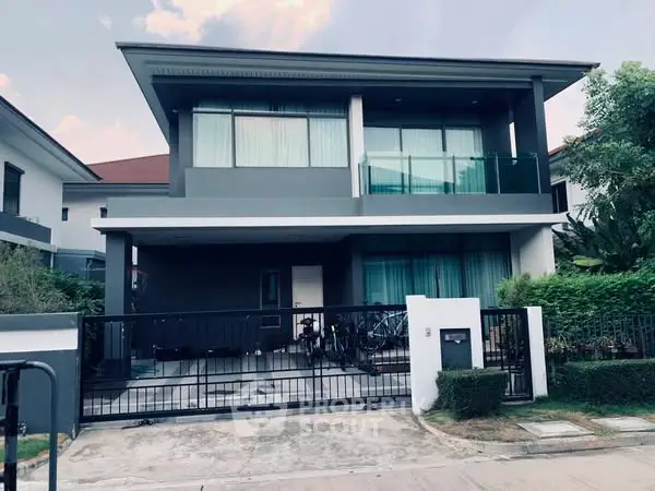 Modern two-story house with sleek design and gated entrance in a suburban neighborhood.