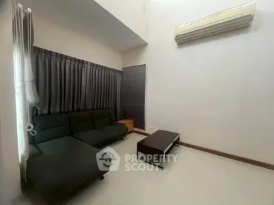 Modern living room with sleek black sofa and air conditioning unit