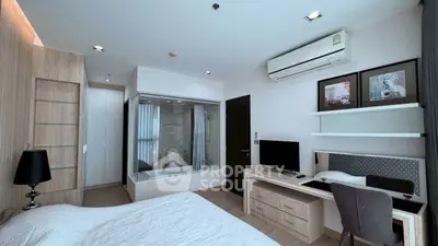 Modern bedroom with integrated glass-walled bathroom and stylish workspace