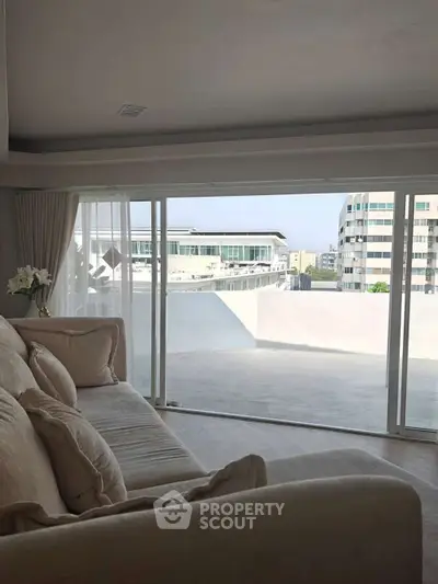 Spacious living room with large sliding doors opening to a balcony with city views.