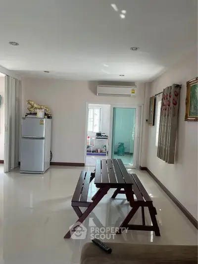 Spacious living area with modern decor and natural light, featuring a dining set and air conditioning.