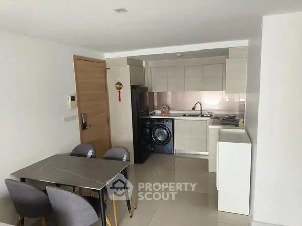 Modern kitchen with dining area, featuring sleek cabinetry and integrated appliances.