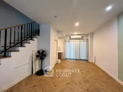 Spacious modern living room with wooden flooring and stylish staircase