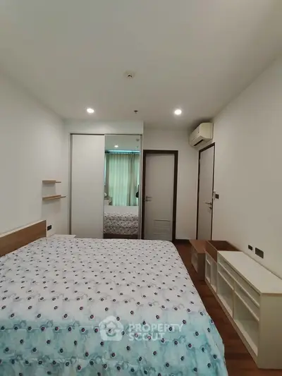 Modern bedroom with stylish decor and ample natural light, featuring a cozy bed and sleek storage solutions.