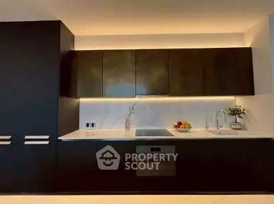 Modern kitchen with sleek dark cabinets, built-in oven, and stylish lighting