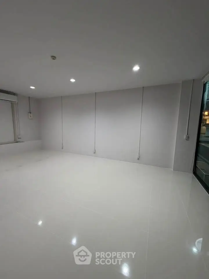 Spacious empty room with glossy white tiles and modern lighting, perfect for customization.