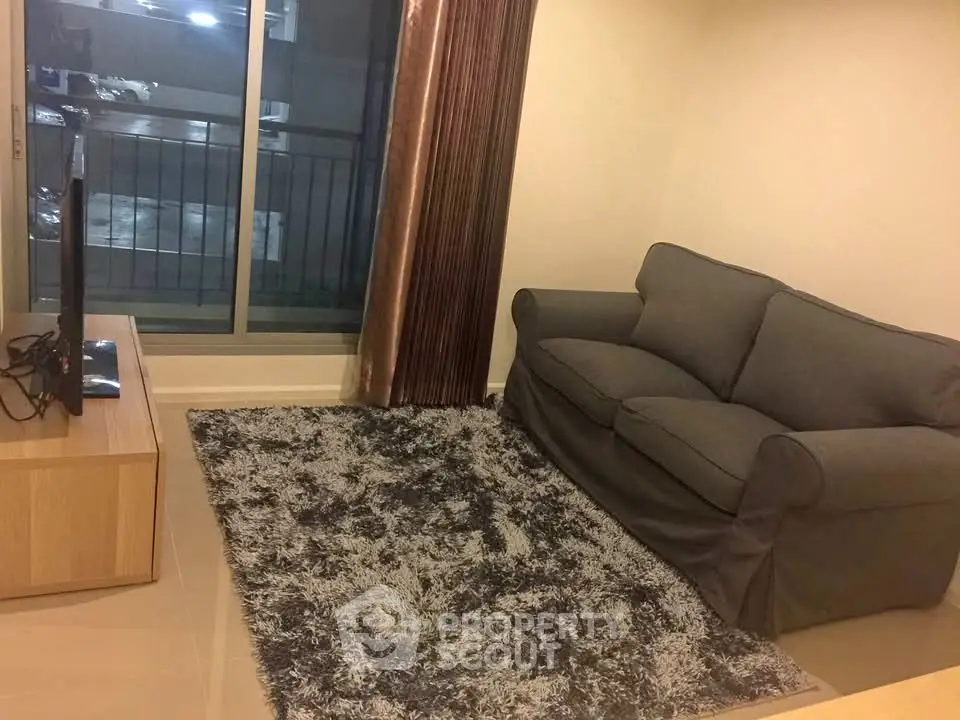 Cozy living room with plush gray sofa and modern TV setup, perfect for relaxation.