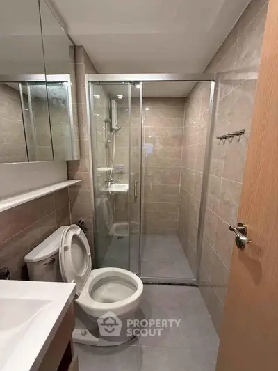 Modern bathroom with glass shower enclosure and sleek fixtures in a contemporary apartment.