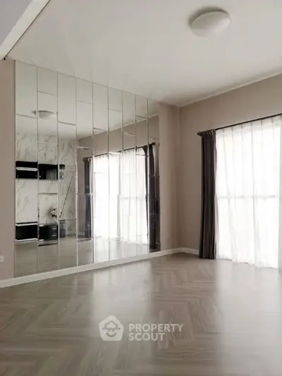 Spacious modern living room with large mirrored wall and elegant flooring