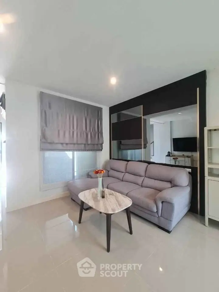 Modern living room with sleek gray sofa and stylish coffee table in a bright, airy space.