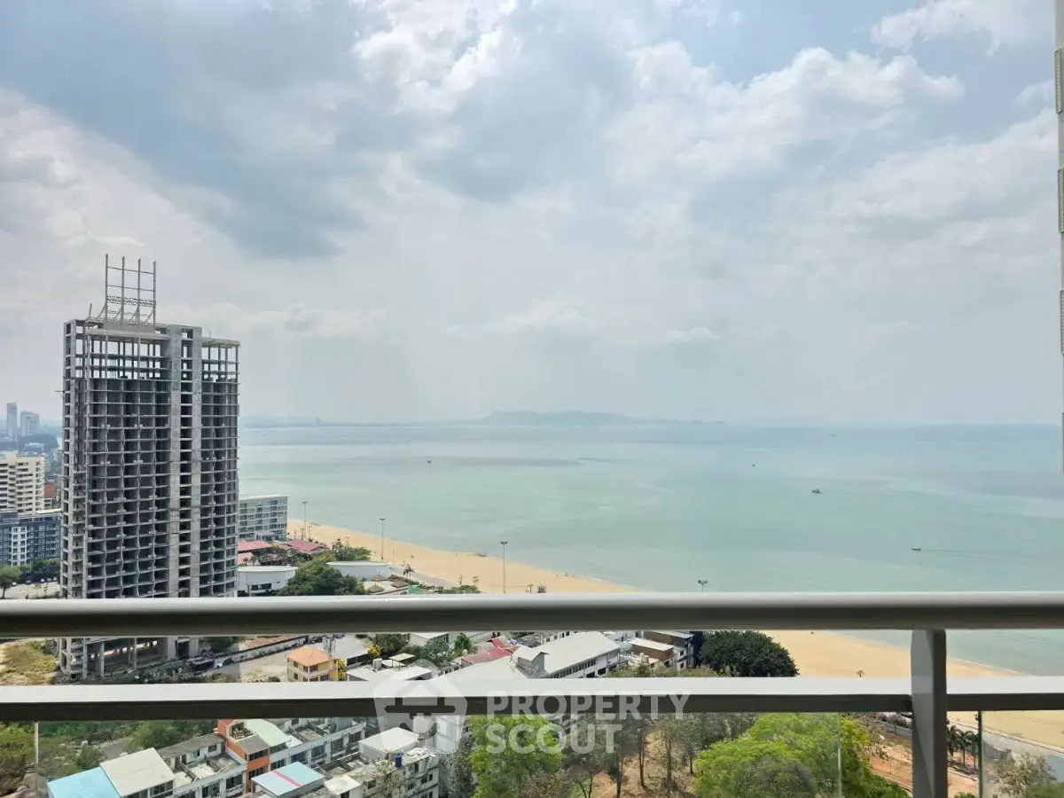 Stunning beachfront view from high-rise balcony overlooking ocean and cityscape.