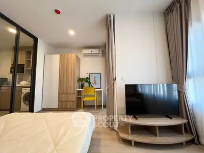 Modern bedroom with TV and workspace, featuring stylish decor and natural light.