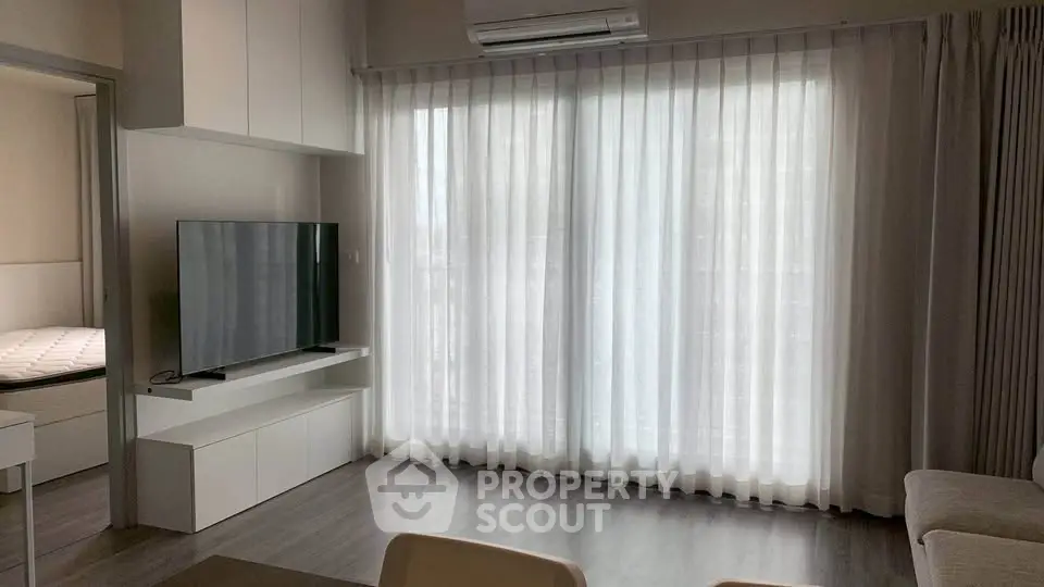 Modern living room with large window and sleek TV setup in a stylish apartment.