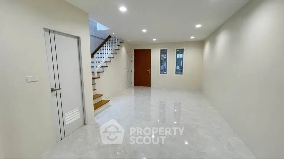 Spacious modern living room with sleek staircase and glossy tile flooring