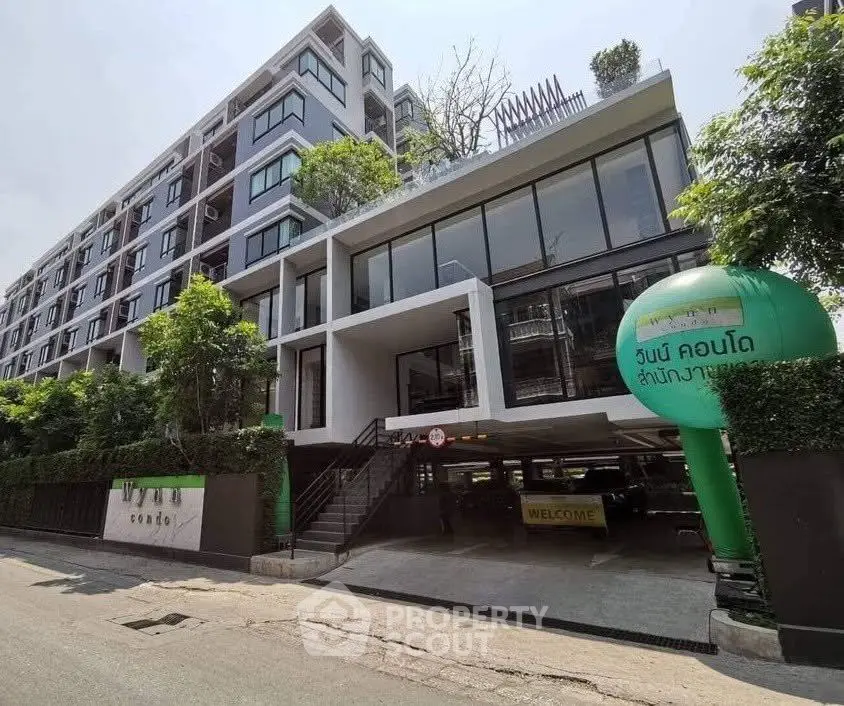 Modern condominium building with sleek design and lush greenery in urban setting.