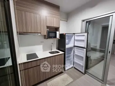 Modern compact kitchen with open fridge and microwave in sleek apartment