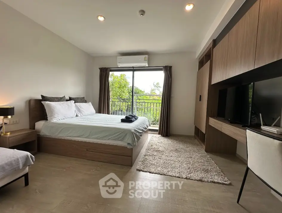 Modern bedroom with balcony view, featuring stylish furniture and natural light.