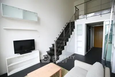 Modern loft-style living room with sleek staircase and minimalist decor