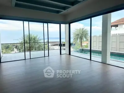 Spacious living room with floor-to-ceiling windows offering stunning pool and ocean views.