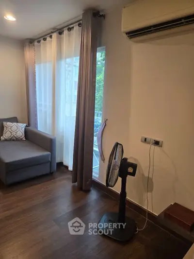 Cozy living room with modern sofa and air conditioning, featuring elegant curtains and wooden flooring.