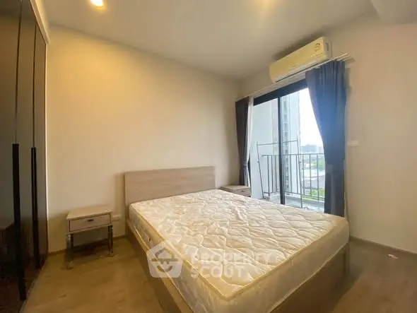 Modern bedroom with balcony view and air conditioning in urban apartment.