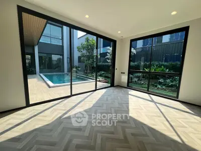 Luxurious modern living room with floor-to-ceiling windows overlooking a private pool and garden.