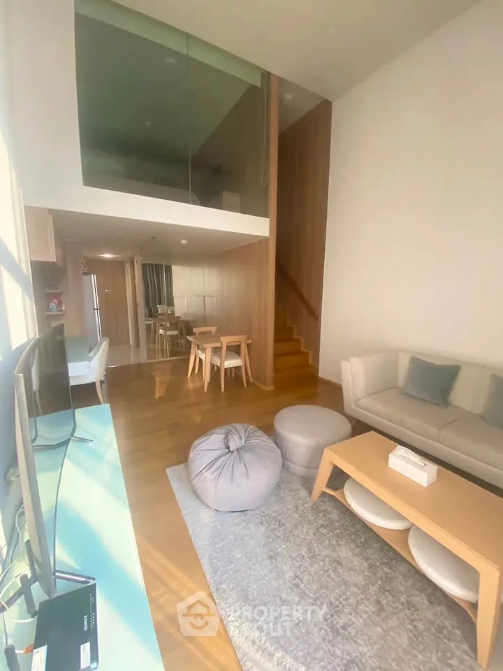 Modern living room with mezzanine, stylish furniture, and abundant natural light.