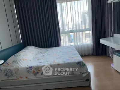 Spacious bedroom with floral bedding and city view through large window.