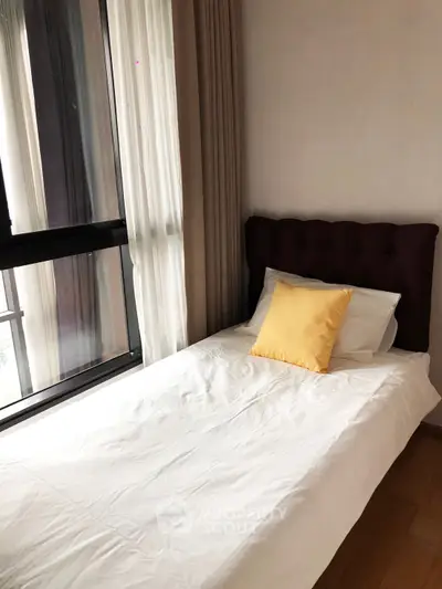 Cozy bedroom with single bed and large window offering natural light