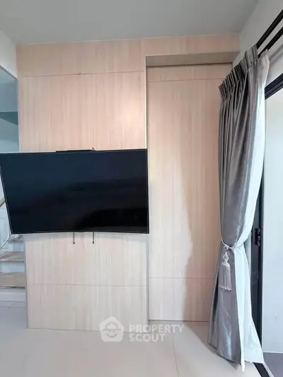 Modern living room with sleek wall-mounted TV and elegant curtains