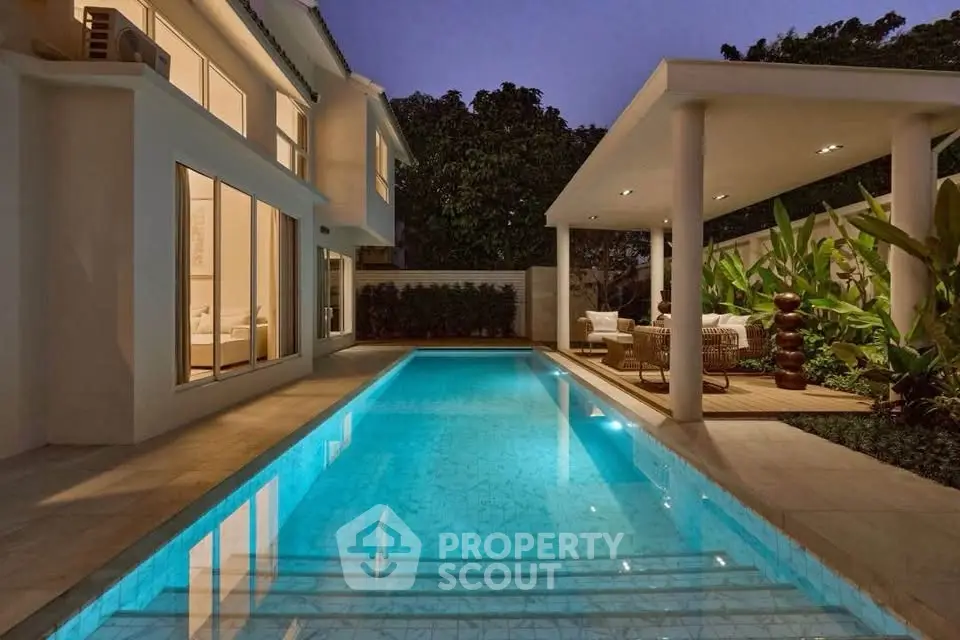 Luxurious modern home with illuminated pool and stylish outdoor seating area at dusk.