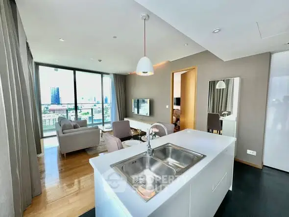 Modern open-plan living room with city view, featuring sleek kitchen island and stylish decor.