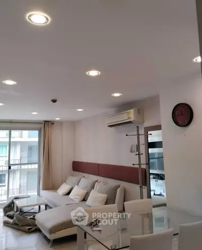 Modern living room with stylish furniture and air conditioning, featuring a glass dining table and cozy sofa.