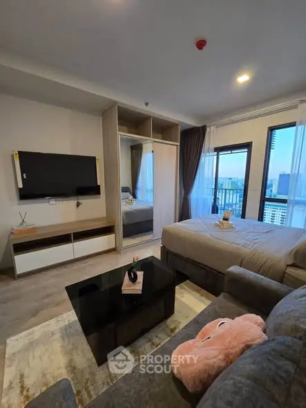 Modern bedroom with city view, featuring a cozy bed, stylish TV setup, and elegant decor.