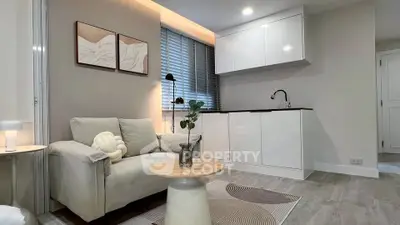Modern living room with cozy sofa and sleek kitchenette in open layout apartment.