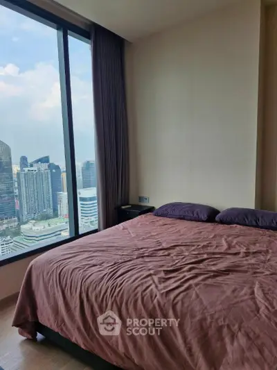 Luxurious bedroom with stunning city view from floor-to-ceiling window in modern high-rise apartment.